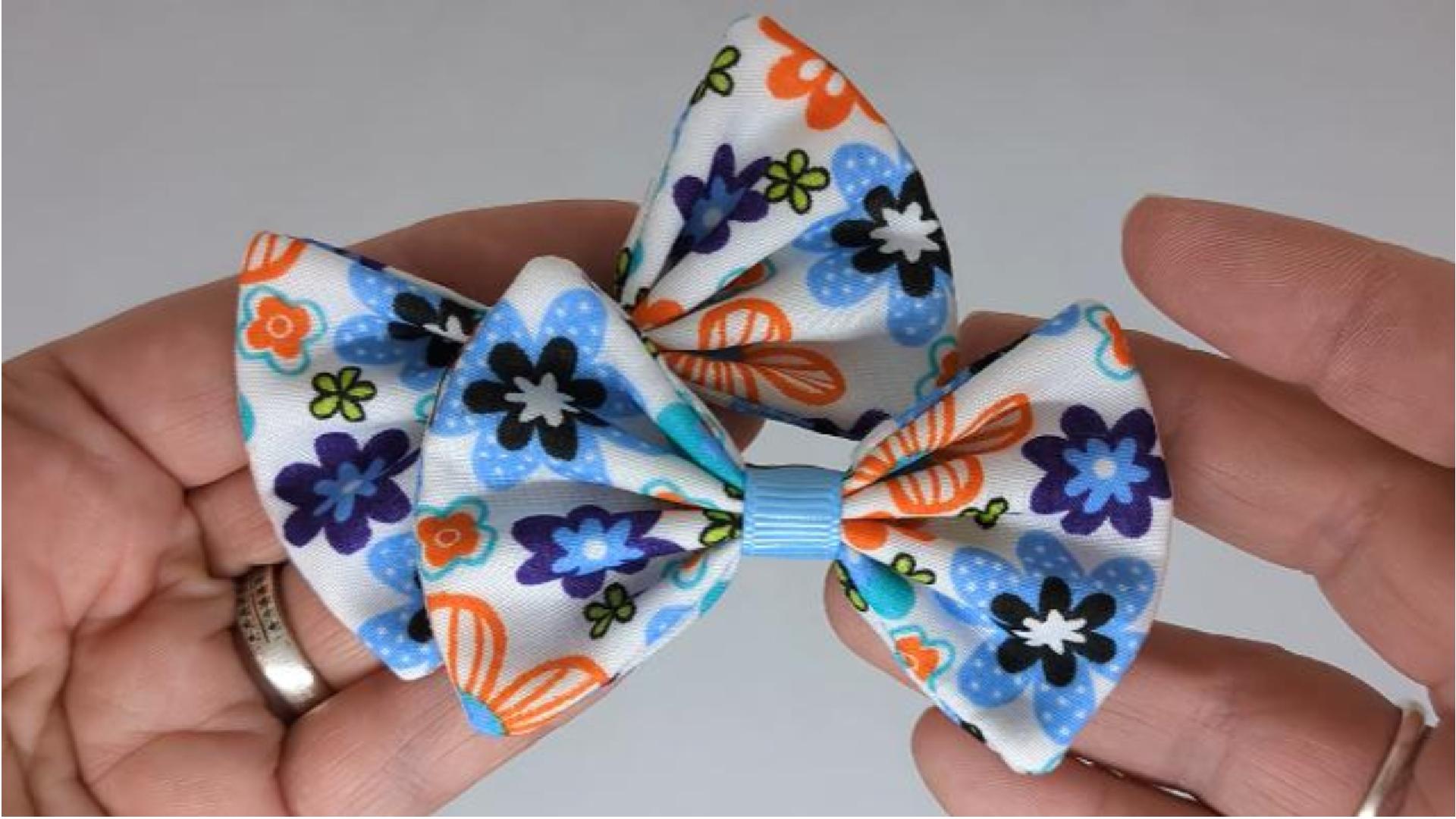 Close-up of funky floral fabric hair bows on alligator clips, measuring 7cm x 5cm, showcasing the vibrant blue, orange, and white floral pattern.