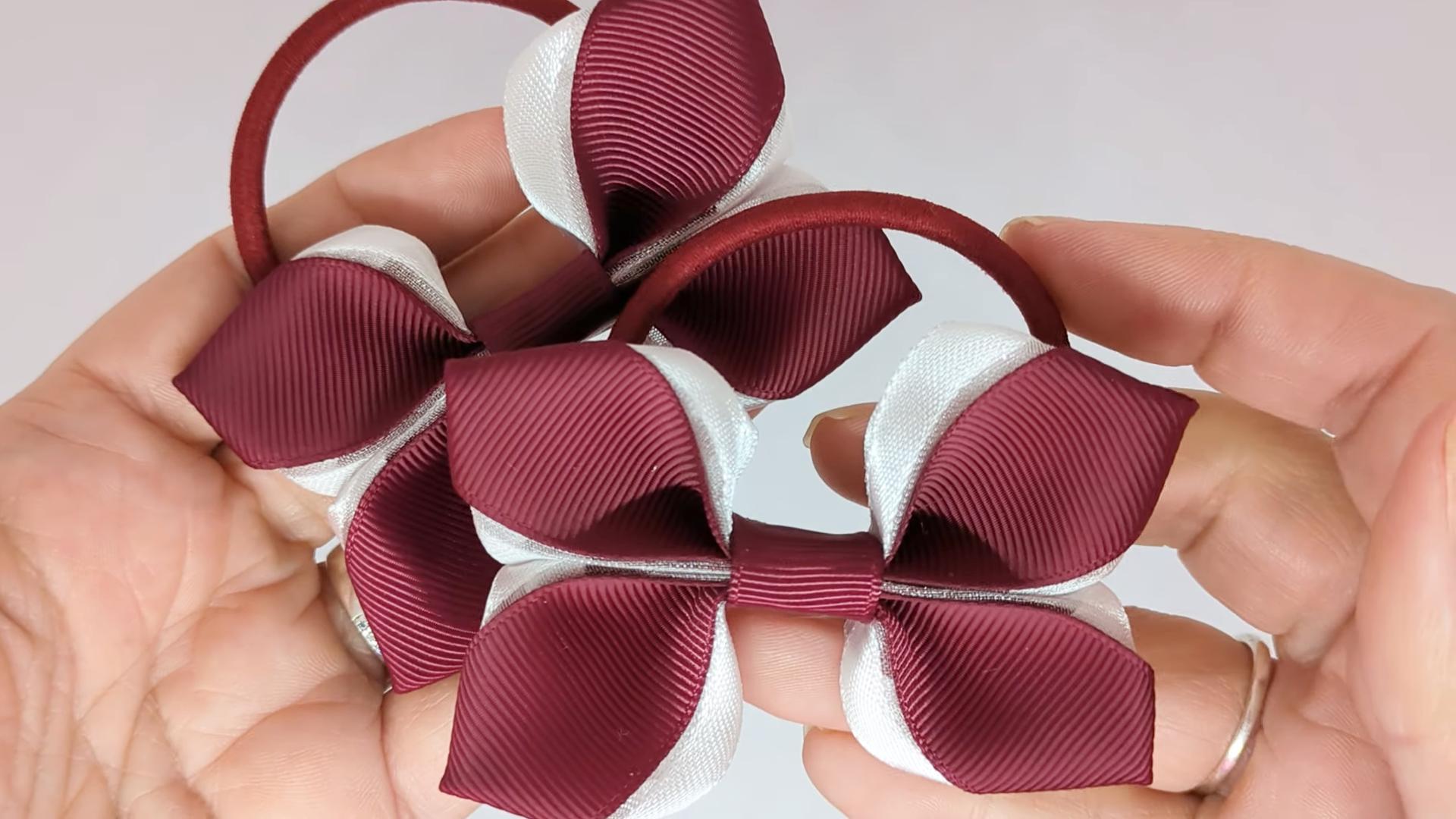Close-up of burgundy and white organza hair bows on thick bobbles, measuring 9cm x 6cm, showcasing the delicate organza ribbon and contrasting colours.