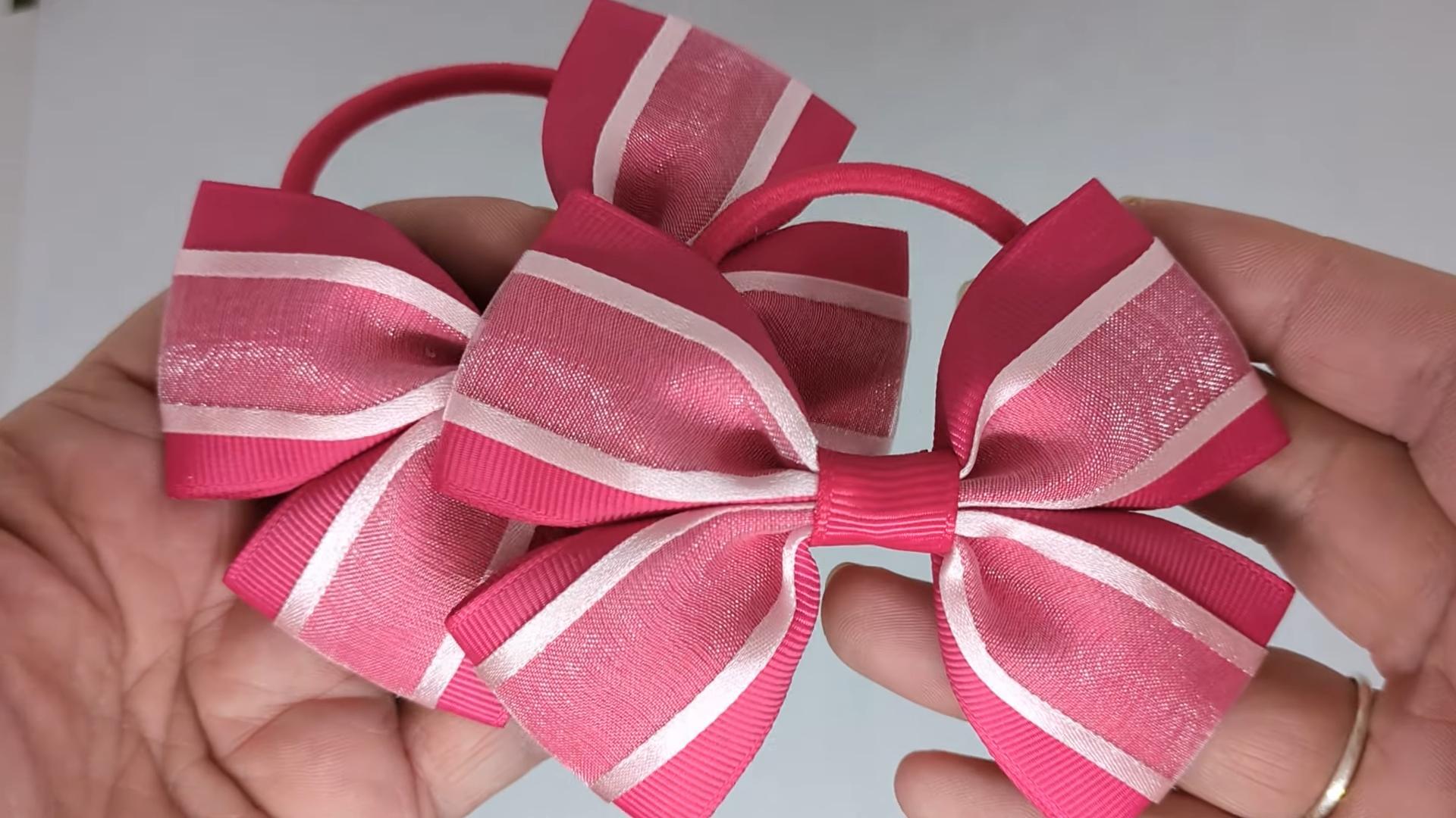 Close-up of cerise pink and baby pink hair bows on thick bobbles and alligator clips, showcasing the combination of grosgrain and organza ribbon.