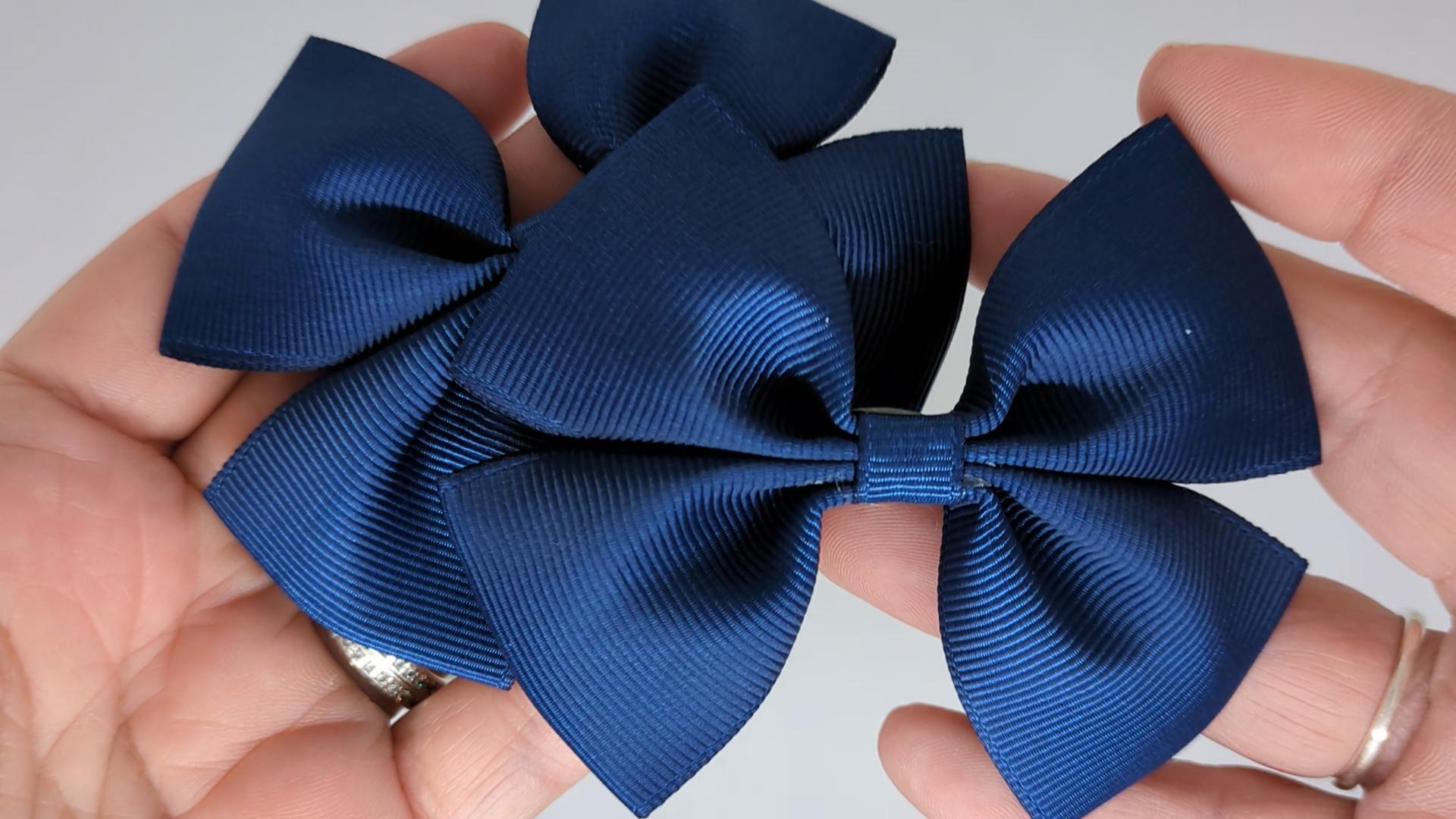 Close-up of navy blue grosgrain ribbon hair bows on alligator clips, measuring 8cm x 6cm, highlighting the smooth texture and deep navy colour.