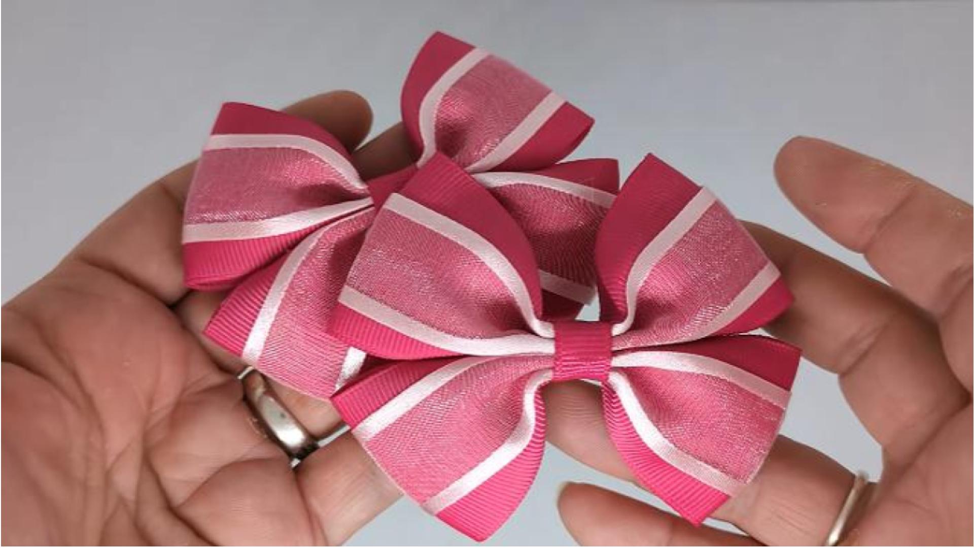 Close-up of cerise pink and baby pink hair bows on thick bobbles and alligator clips, showcasing the combination of grosgrain and organza ribbon.